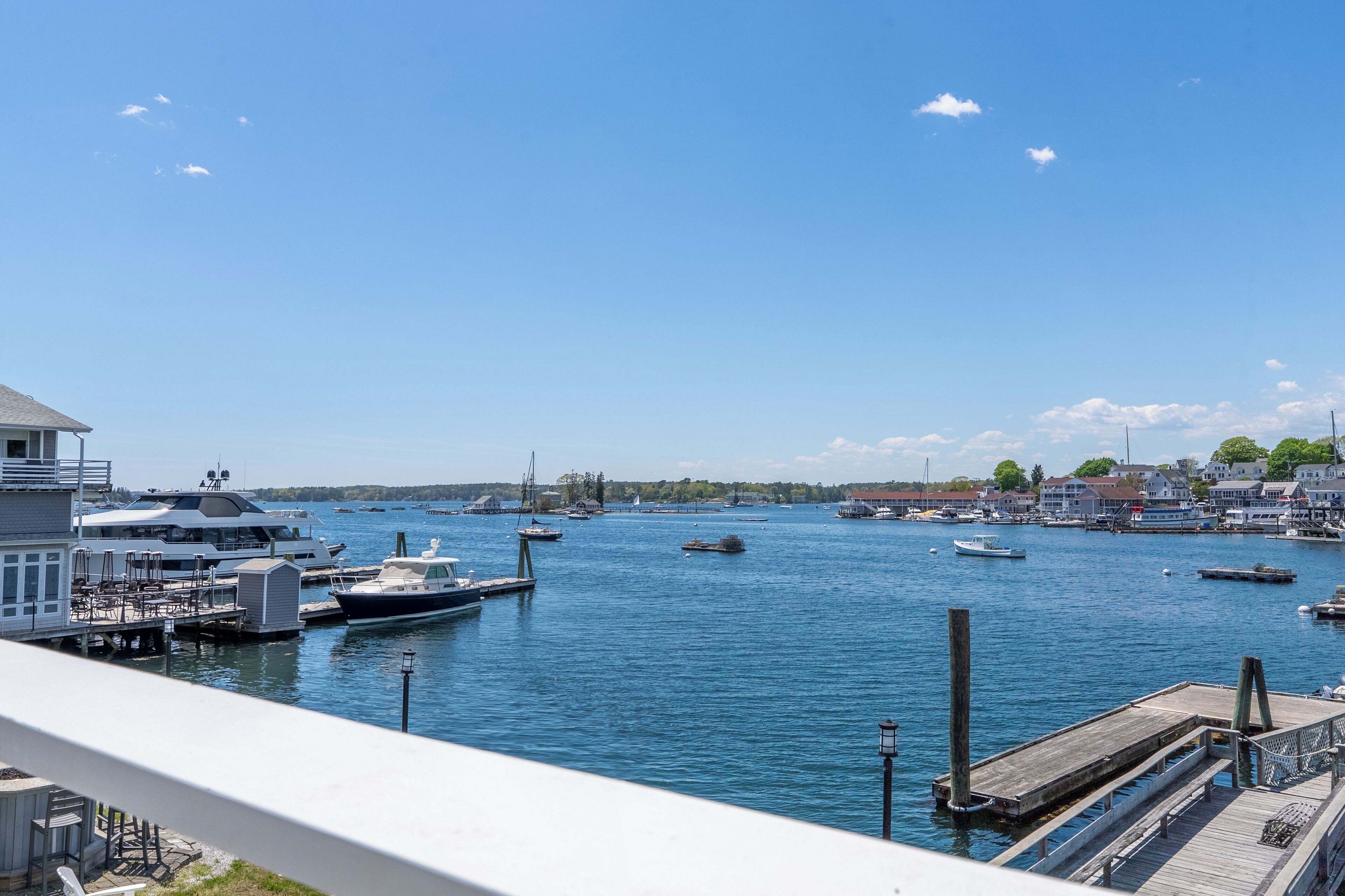 A marina with boats docked, a pier, and buildings in the background.