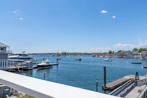 A marina with boats docked, a pier, and buildings in the background.