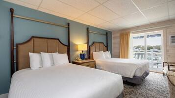 A hotel room with two beds, a nightstand with a lamp, a window with a view, and a balcony.