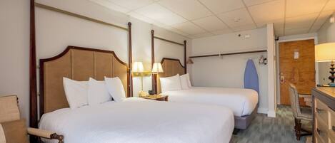 A hotel room with two beds, a desk, a chair, a wardrobe, and a door.