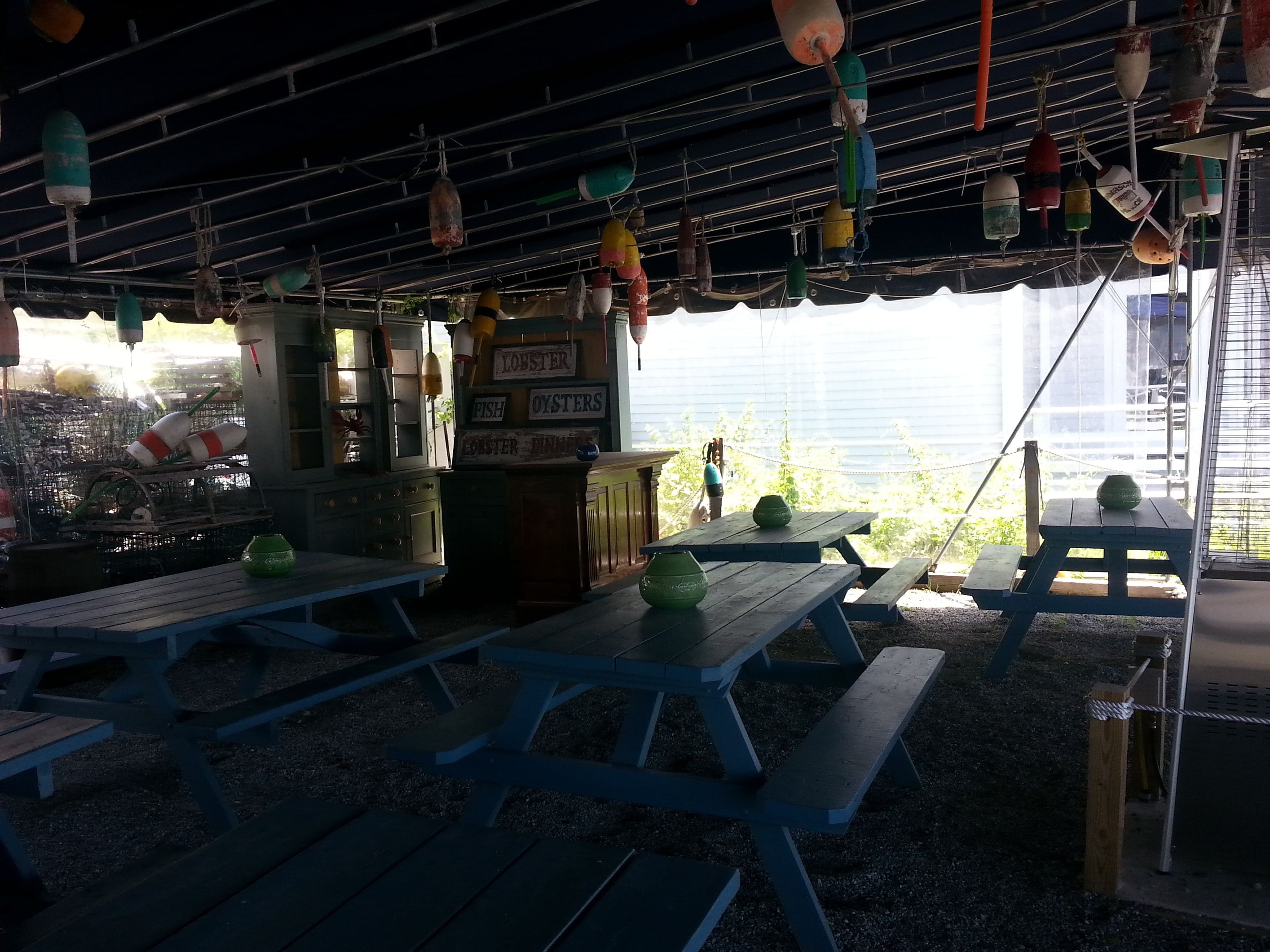 Un espacio de comedor al aire libre con mesas de picnic y adornos colgantes.