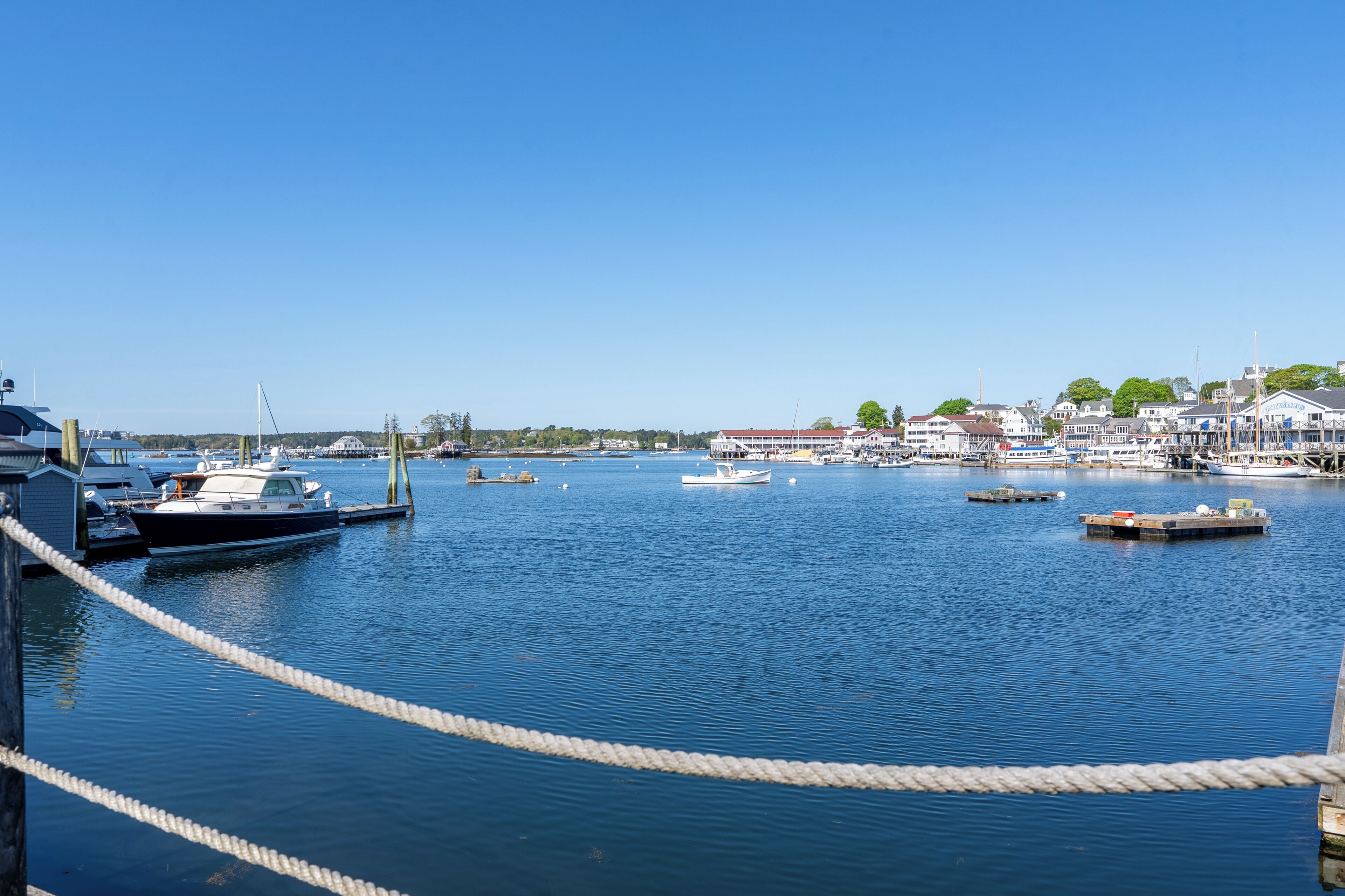 Een jachthaven met aangemeerde boten, een heldere lucht en gebouwen op de achtergrond.