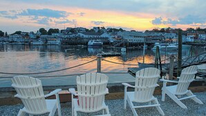 A waterfront view with three Adirondack chairs facing a marina with boats docked. - Boothbay Harbor Inn (Boothbay Harbor)