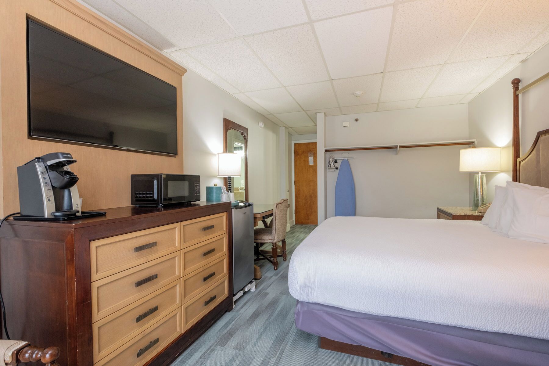Een hotelkamer met een bed, een dressoir, een magnetron, een televisie, een bureau en een stoel.