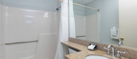 Un baño con bañera, lavamanos, espejo y perchero para toallas.