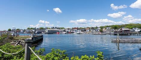 A harbor with boats docked, a wooden pier, and buildings in the background.