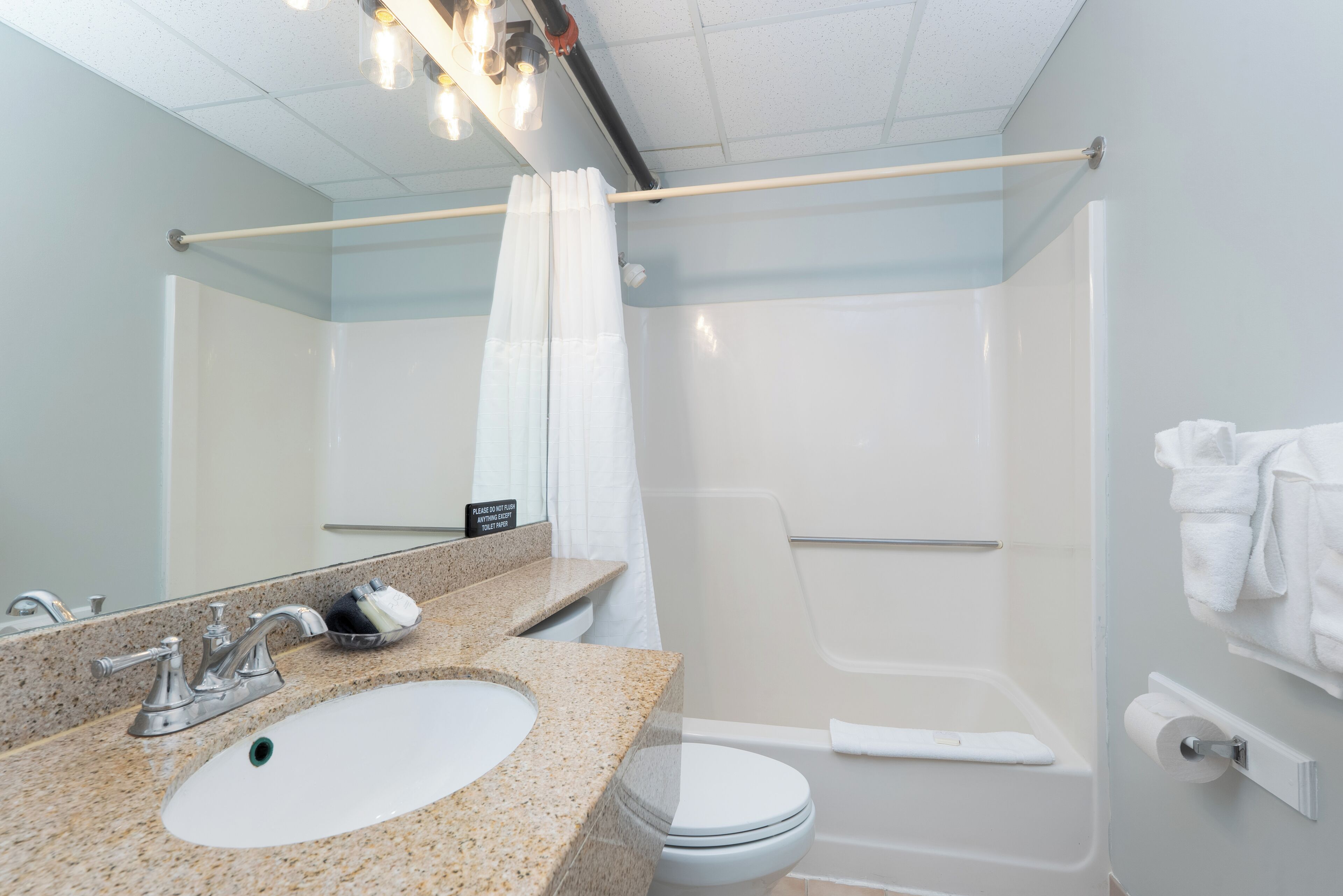 A modern bathroom with a granite sink, a white toilet, and a glass-enclosed shower.