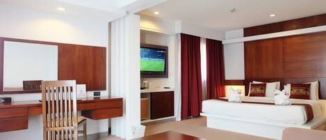 A hotel room with a desk, chair, bed, and a television.