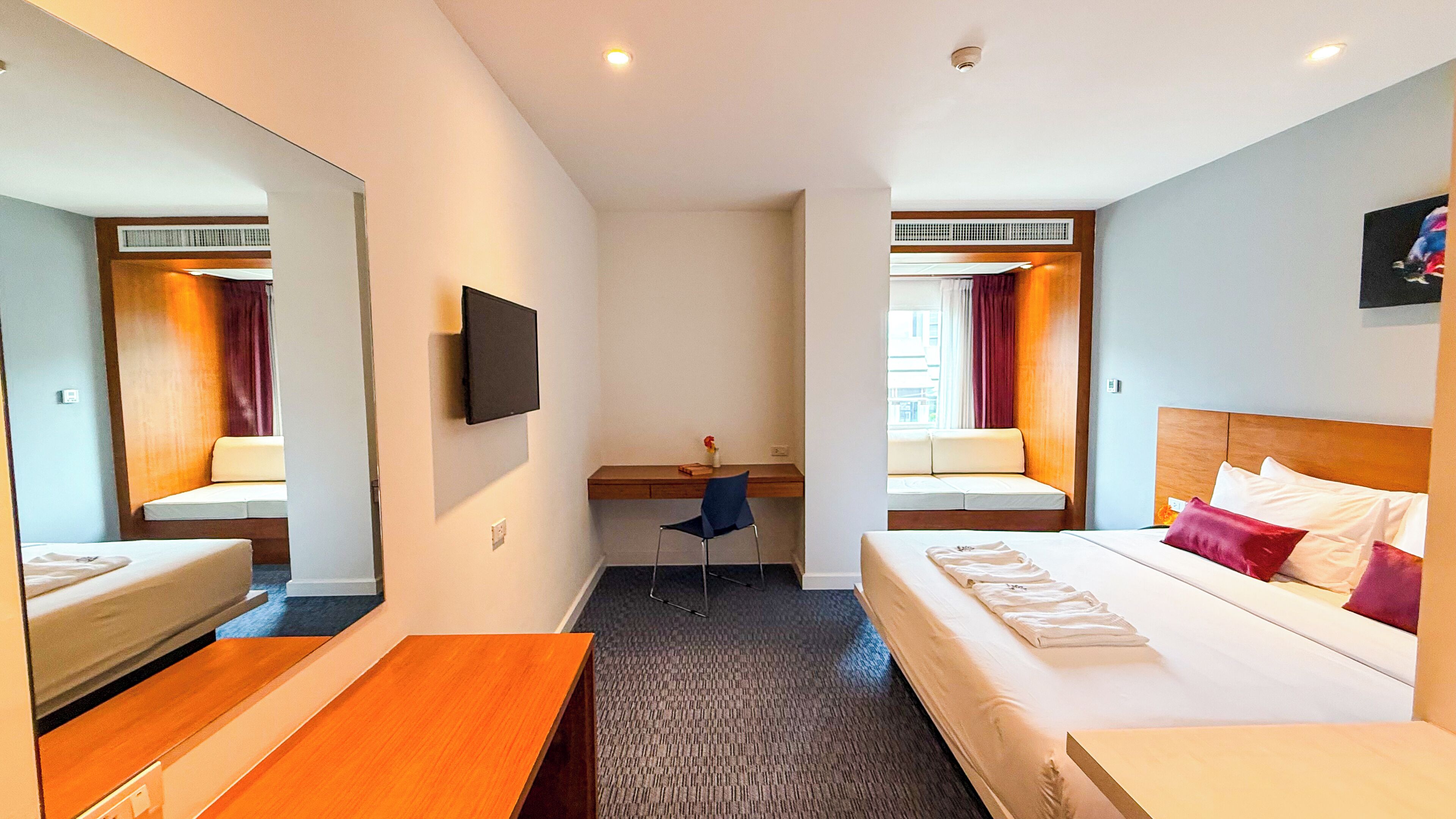 Une chambre d’hôtel équipée d’un lit, d’un bureau, d’une chaise, d’une télévision et d’une fenêtre avec des rideaux.