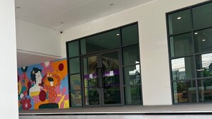 Un edificio moderno con grandes ventanales y un mural colorido en la pared.