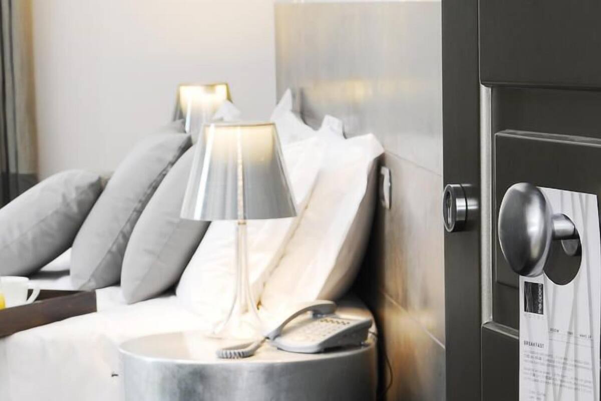 A hotel room with a bed, bedside table, lamp, and a tray of breakfast items.