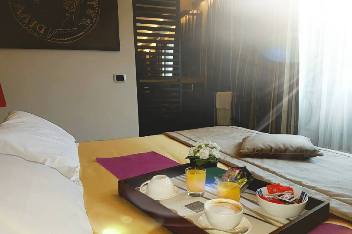 A hotel room with a bed, a tray with breakfast items, and a window with curtains.