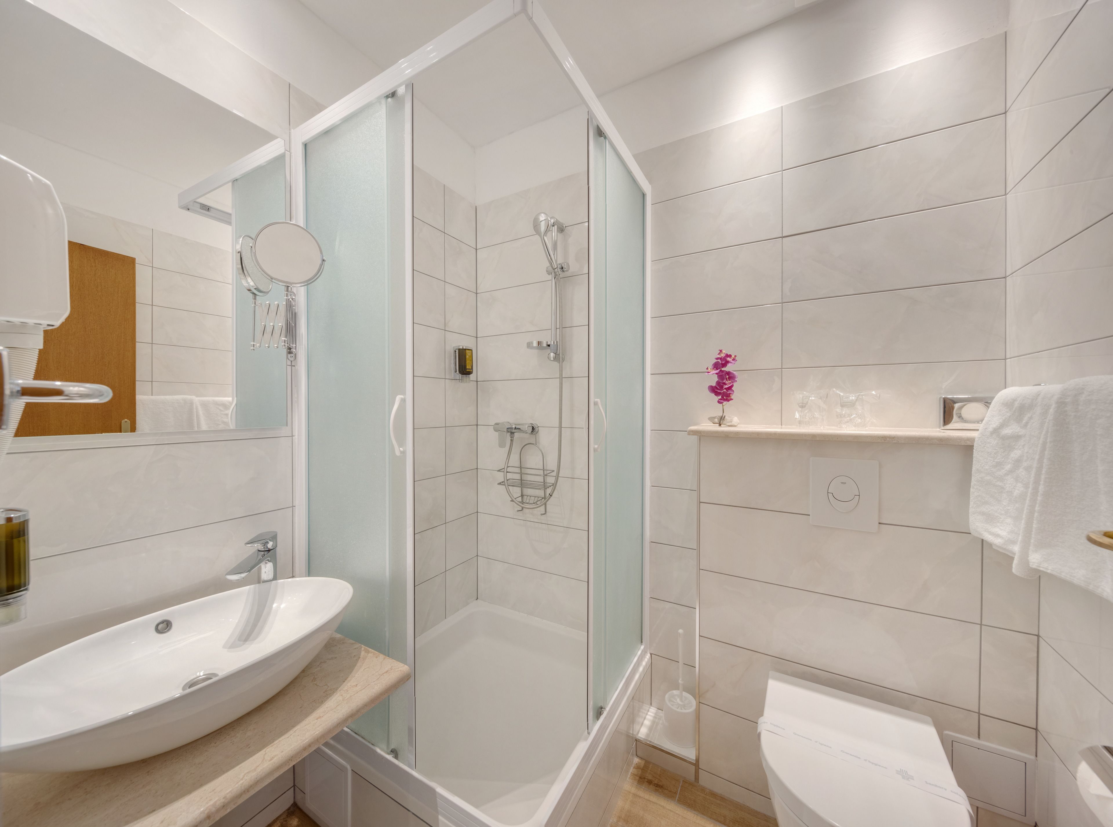 A modern bathroom with a glass-enclosed shower, a sink, and a toilet.