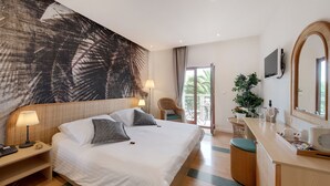 A modern hotel room with a large bed, a desk with a laptop, a large mirror, and a balcony with a view of palm trees. - Hotel Villa Adriatica - Adults only (Supetar)