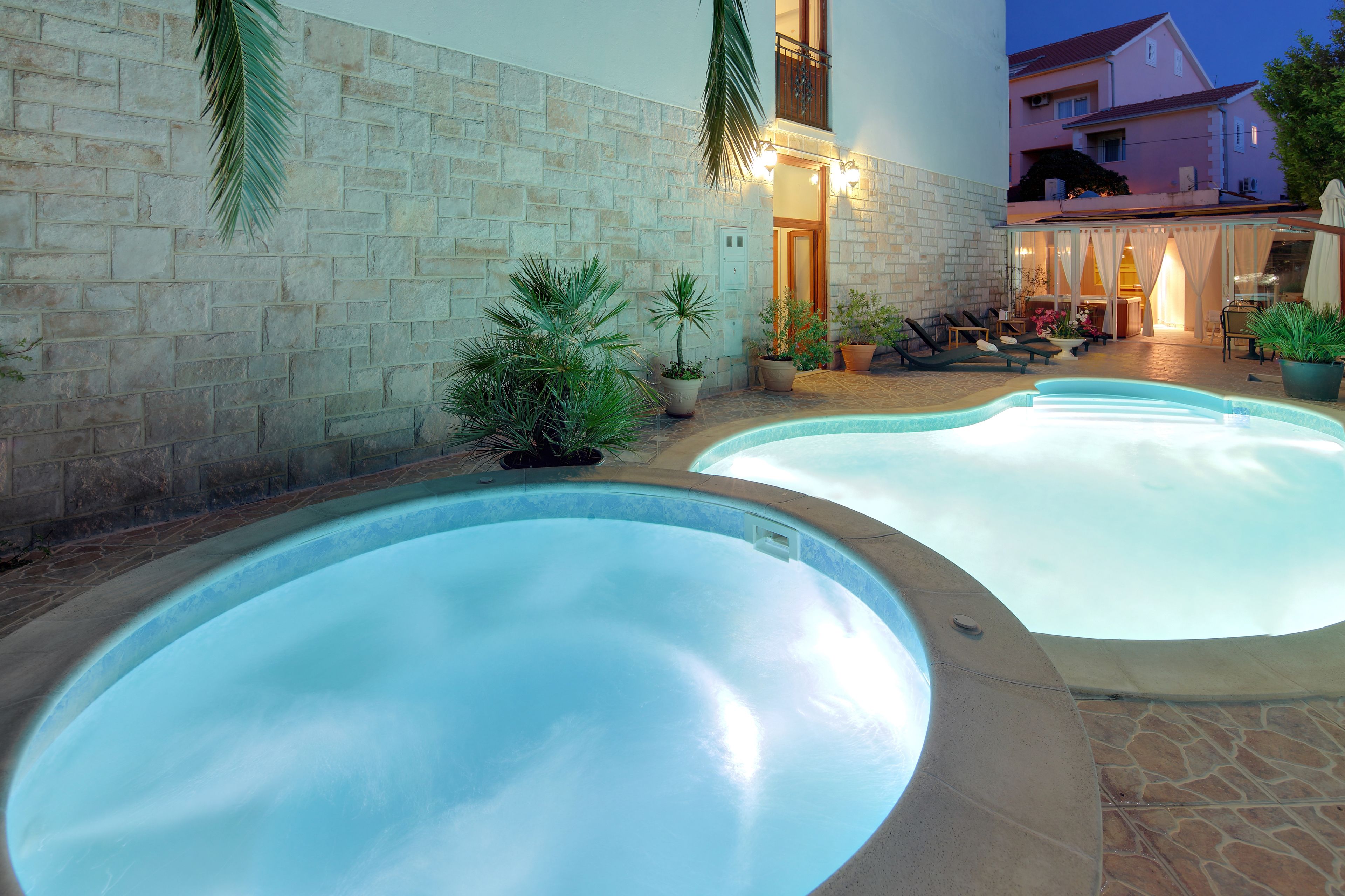 Ein Poolbereich mit zwei Whirlpools, Steinmauern und Topfpflanzen.