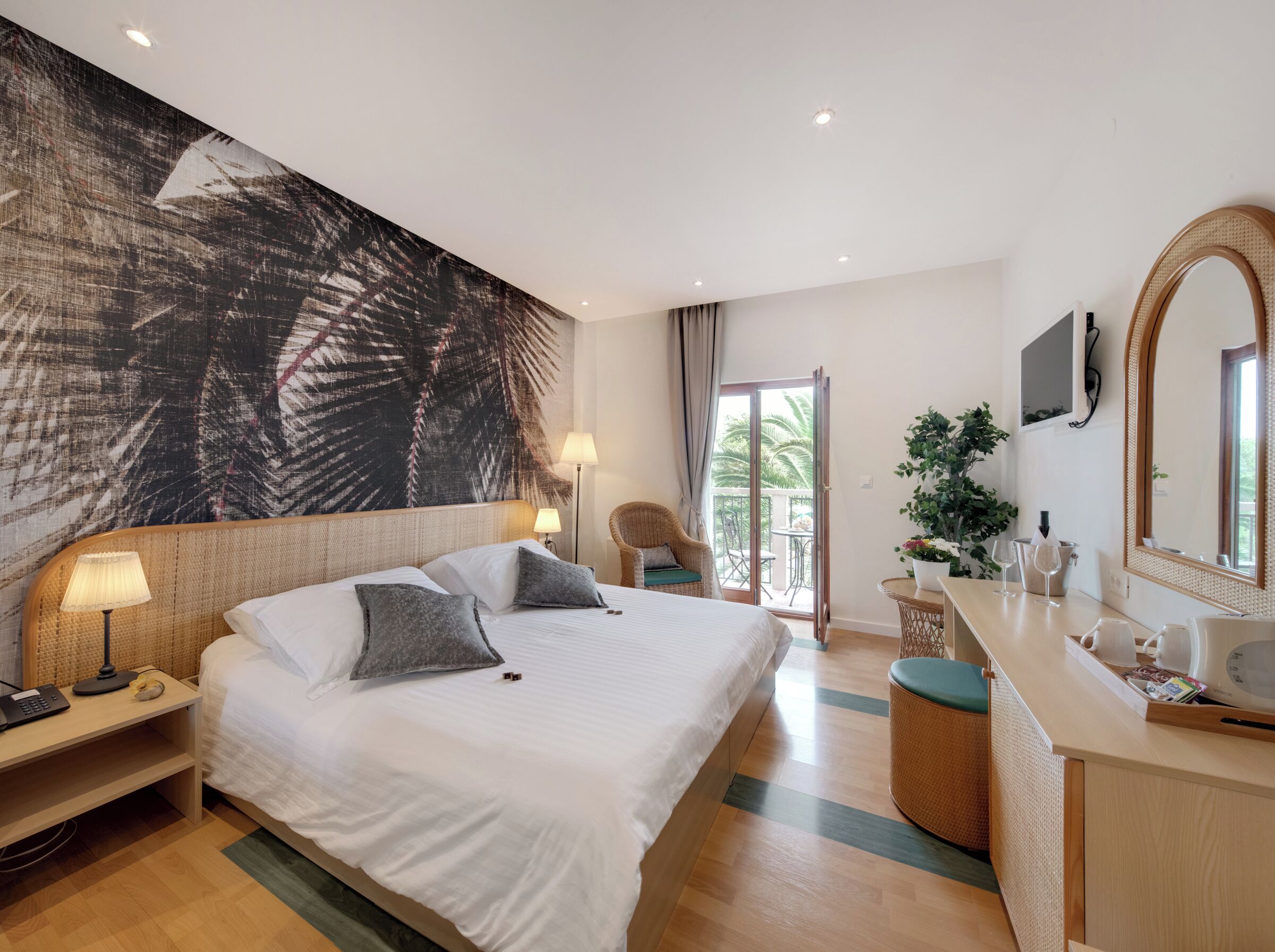 Habitación de hotel con una cama grande, un escritorio con una computadora portátil, un espejo redondo y vistas al exterior.