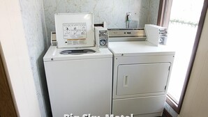 A compact laundry area with a front-loading washer and a stacked dryer. - Big Sky Motel (Superior)