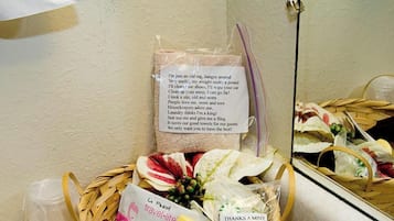 A bathroom with a mirror, a basket of toiletries, and a note on the wall.