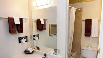 Un baño con lavamanos, espejo, toallero y zona de ducha.