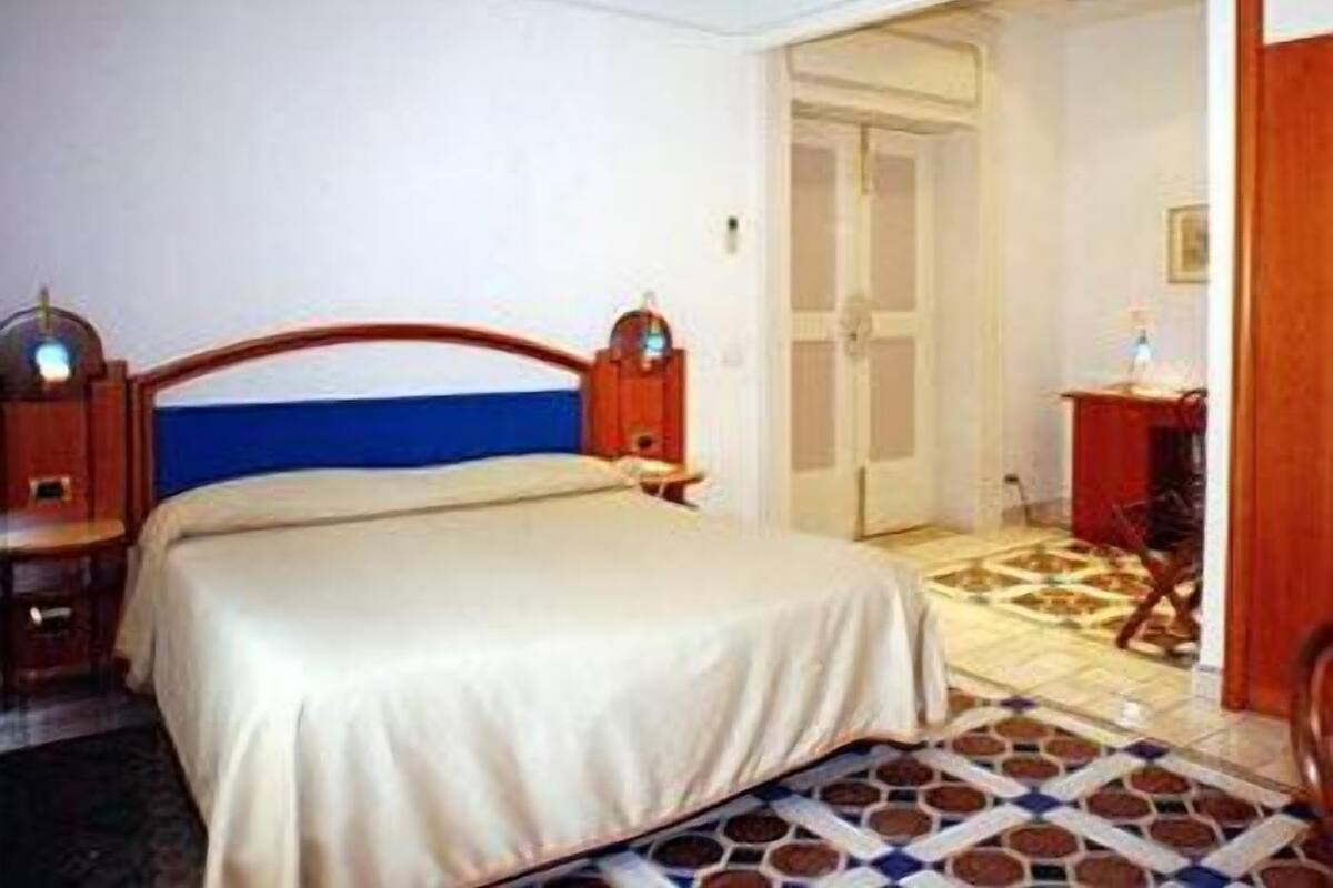 A hotel room with a bed, a desk, and a chair.