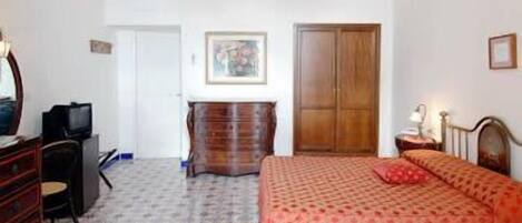 A bedroom with a bed, dresser, and a television.