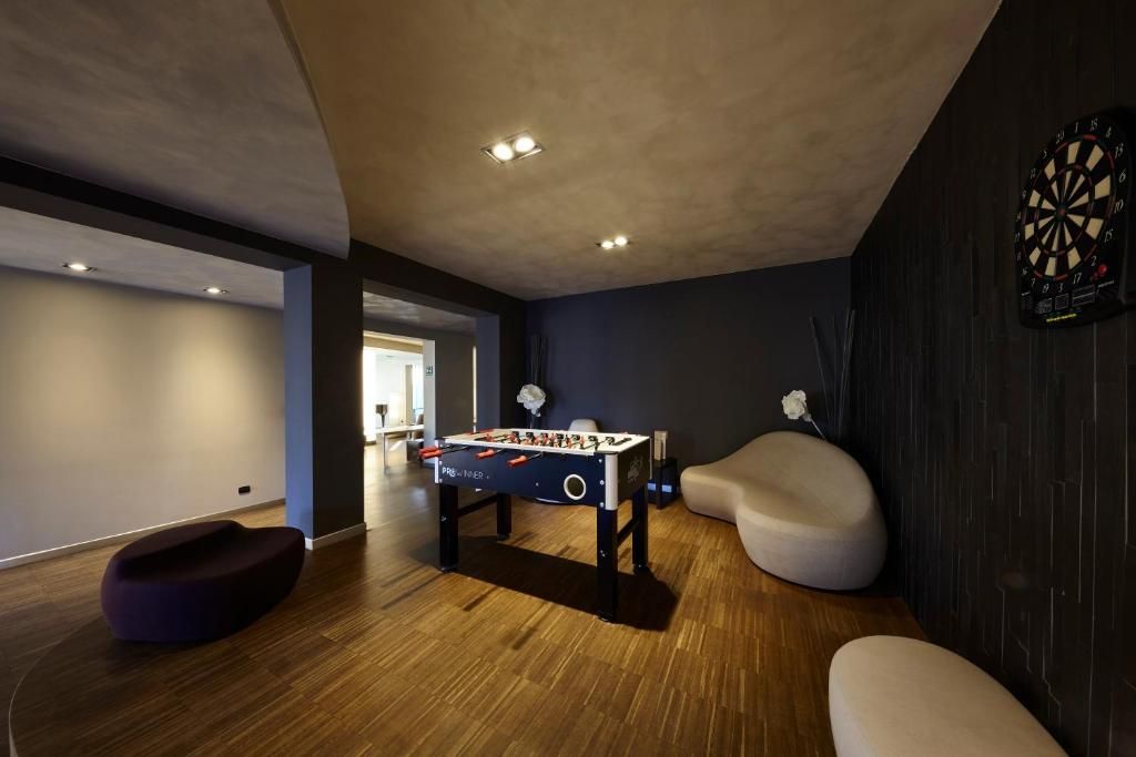 A modern room with a foosball table, a bean bag chair, and a dartboard.