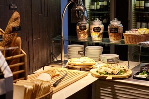 Zona de bufé con diferentes opciones de comida, como pizza, sándwiches y una variedad de quesos.