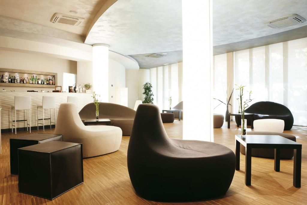 Un área de lounge moderna con bar, asientos y ventanas amplias.