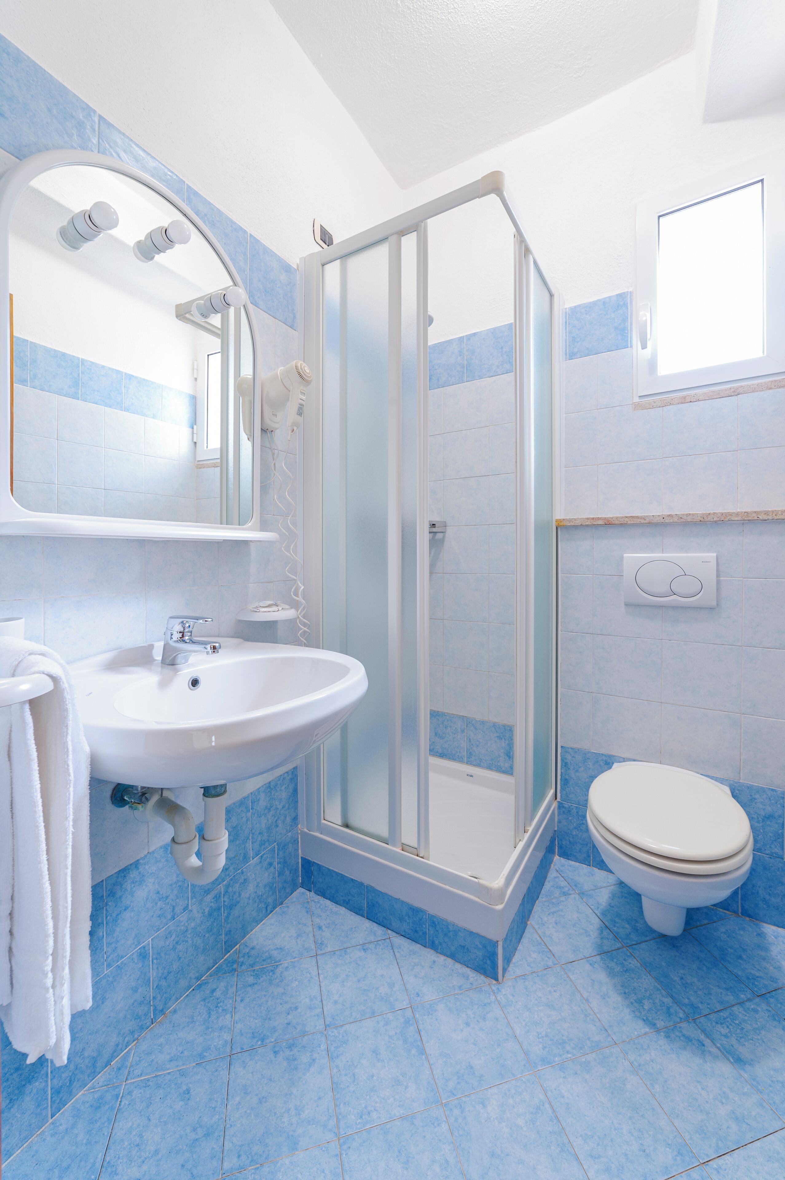 A bathroom with a glass-enclosed shower, a sink with a mirror above it, and a toilet.
