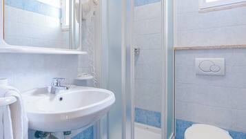 Une salle de bain avec une douche à parois de verre, un lavabo avec un miroir au-dessus et des toilettes.