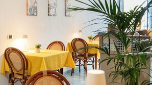 Un espace repas avec des nappes jaunes, des chaises en osier et une plante en pot.