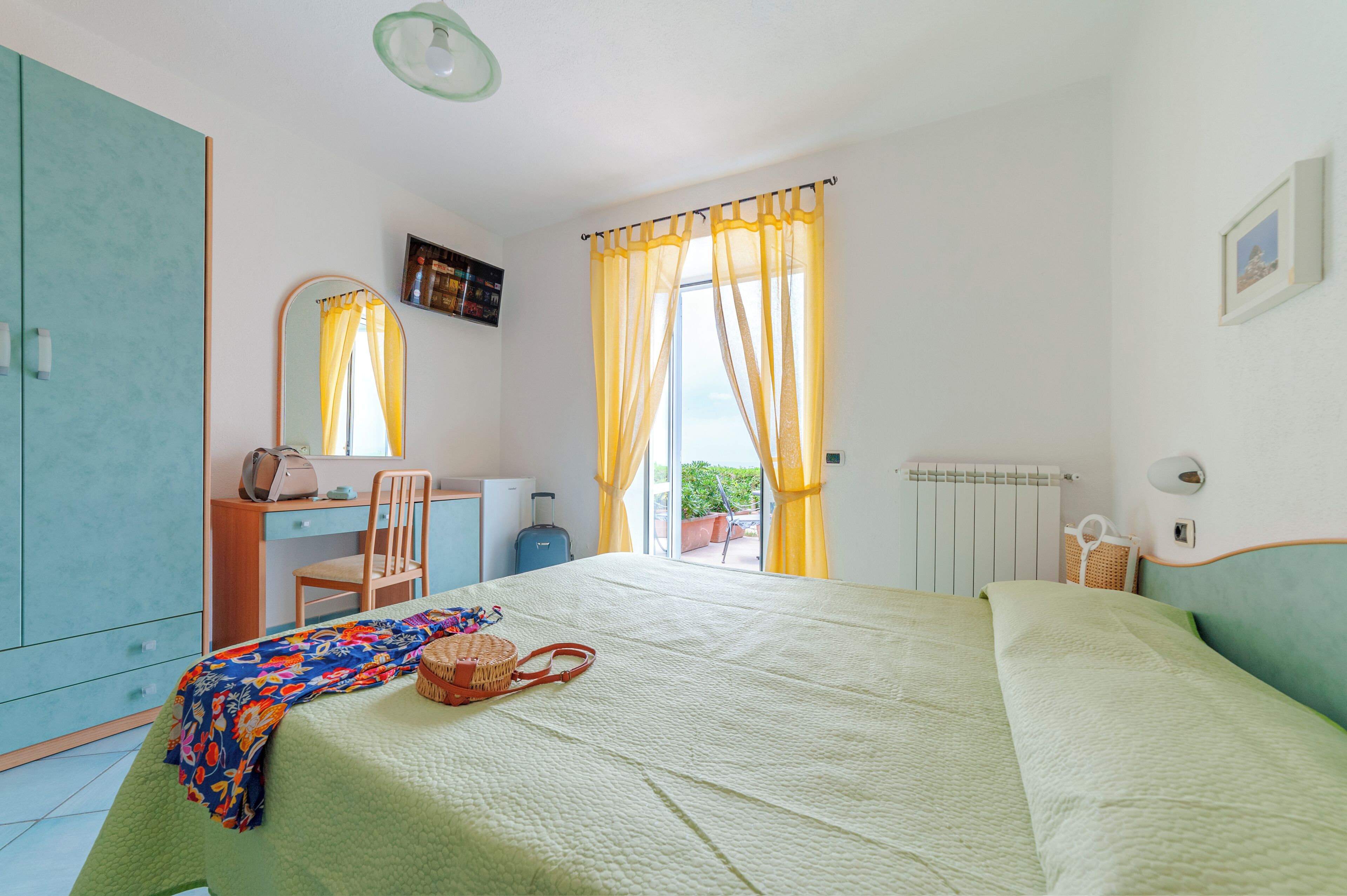 A bedroom with a bed, a desk, a chair, and a window with curtains.