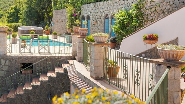Un espace piscine agrémenté de murs en pierre, de plantes en pot et offrant une vue sur les montagnes.