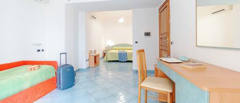 A room with a bed, a desk, a chair, and a suitcase.