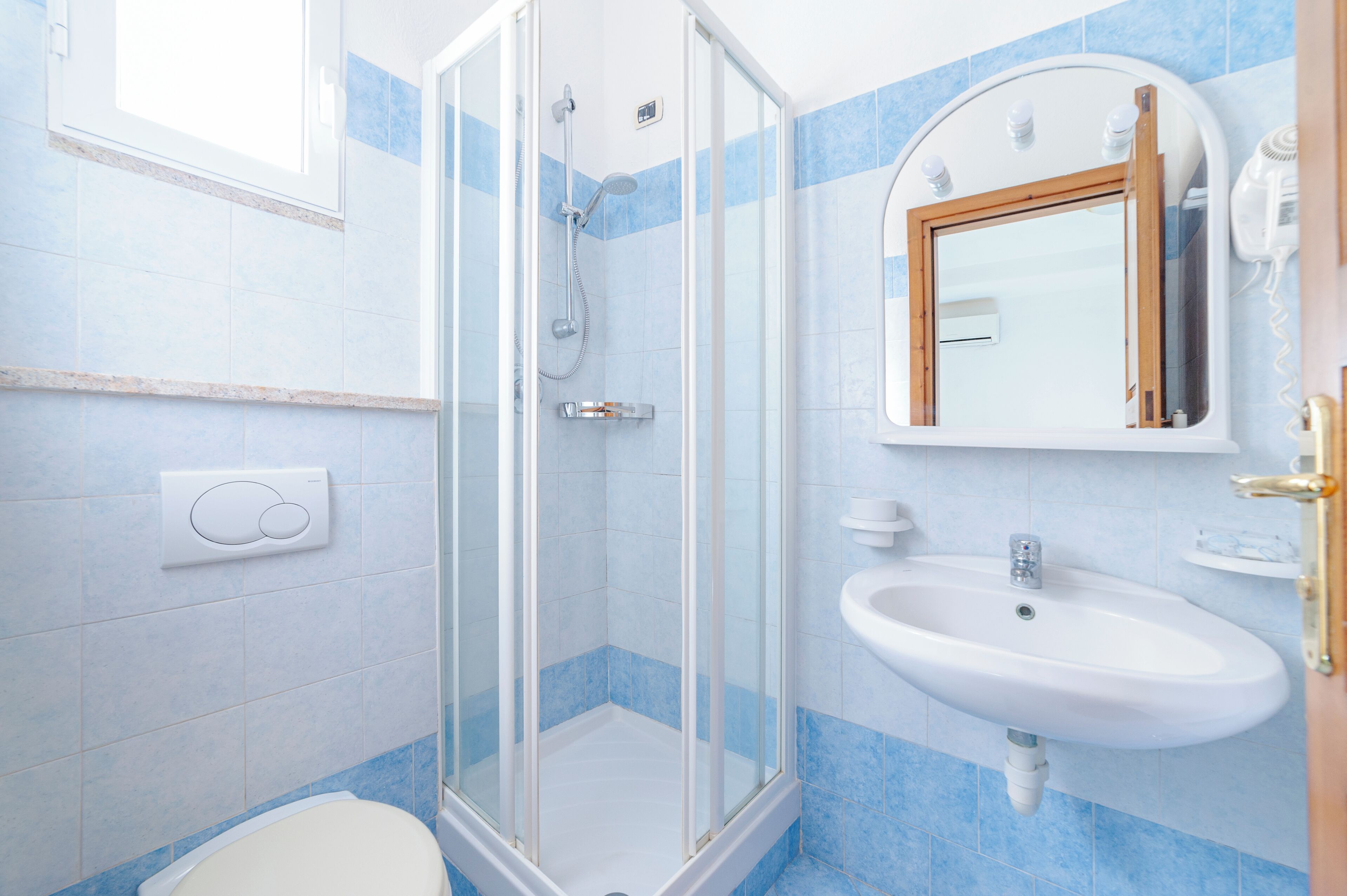 A bathroom with a glass shower enclosure, a sink, and a mirror.