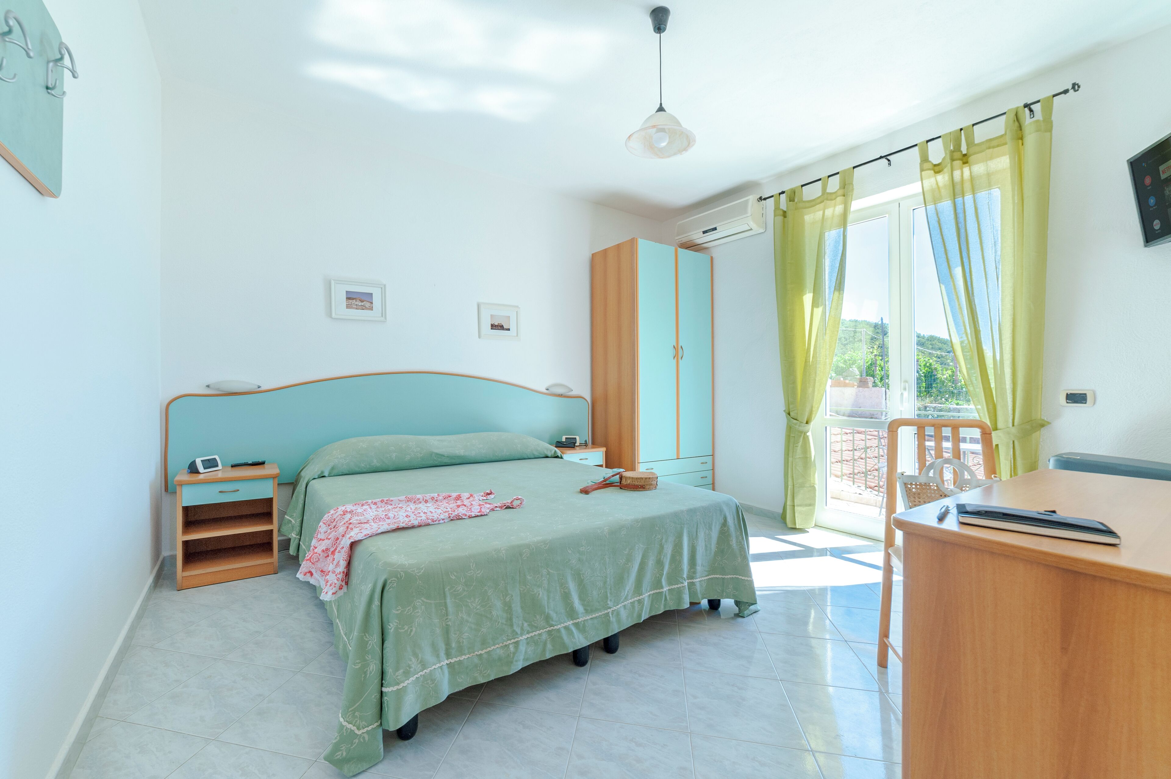 A bedroom with a bed, bedside table, wardrobe, and a desk with a chair.