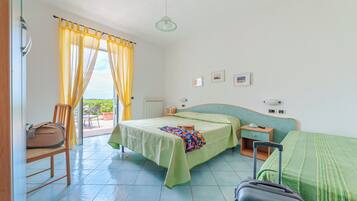 A hotel room with a bed, a suitcase, a chair, a nightstand, and a view of the outdoors.