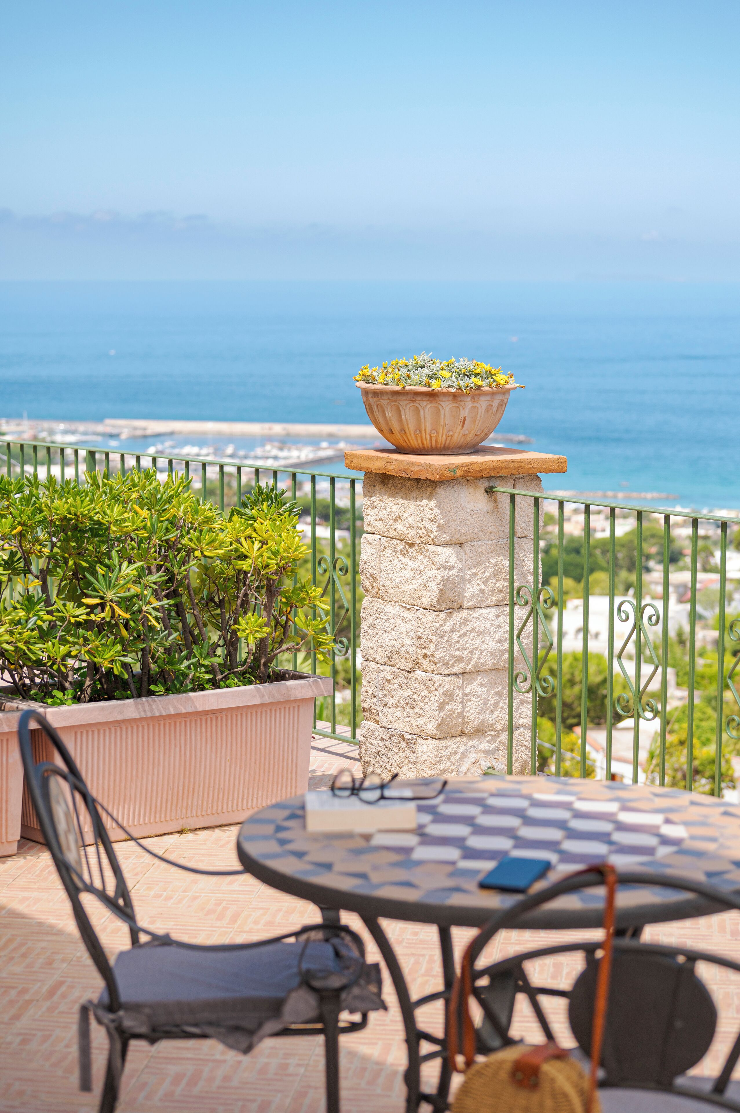 Una terraza con una mesa, sillas, una planta en maceta y vistas al mar.