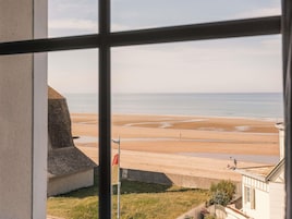 Vista de una playa desde una ventana, con una bandera y un edificio en primer plano.