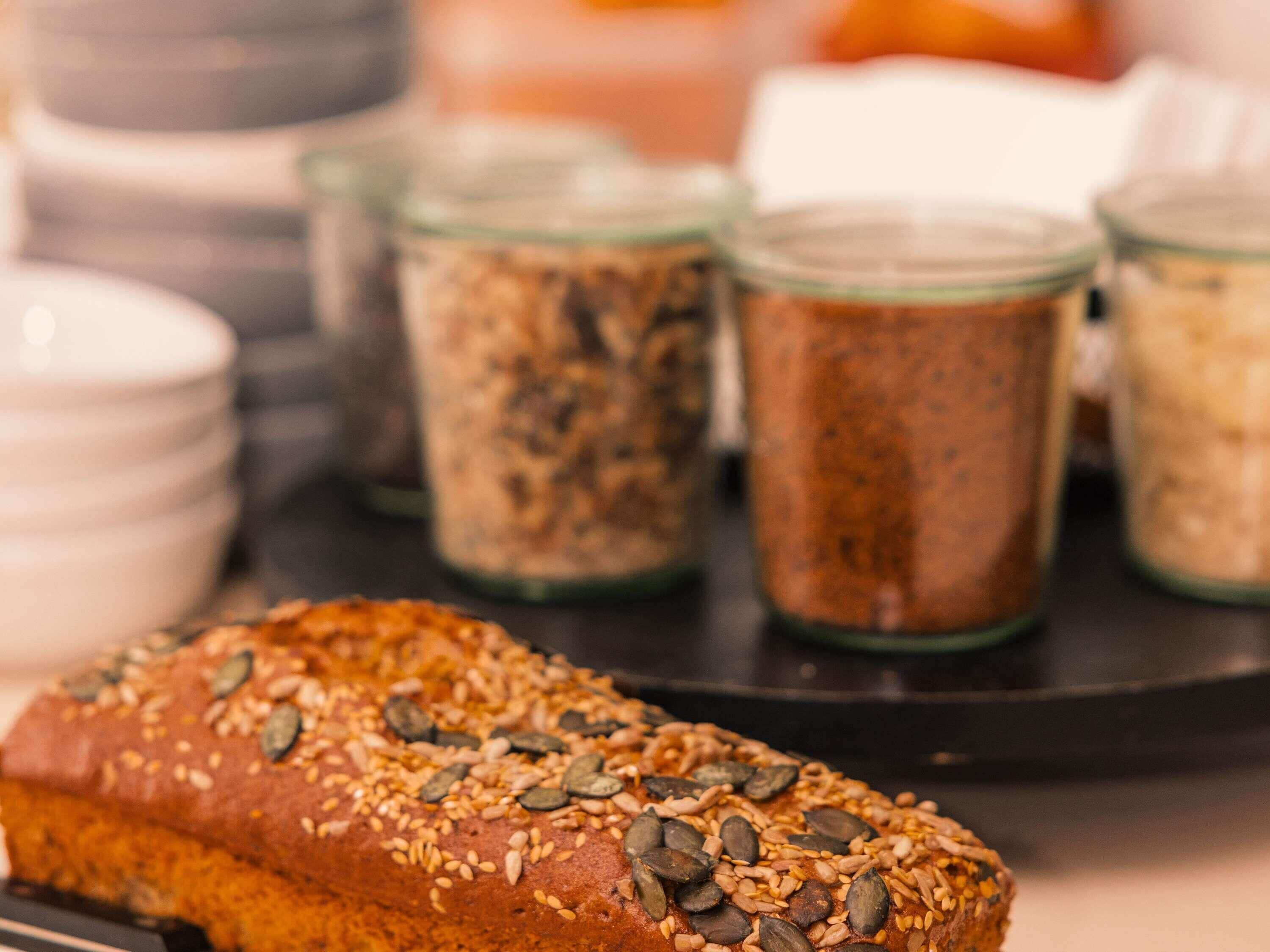 A loaf of seeded bread on a tray with jars of spices in the background.