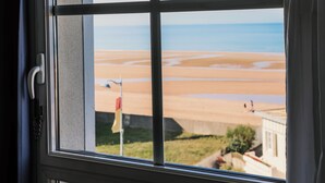 A window with a view of a beach and a flag. - Hotel ibis Styles Deauville Villers Plage (Villers-sur-Mer)