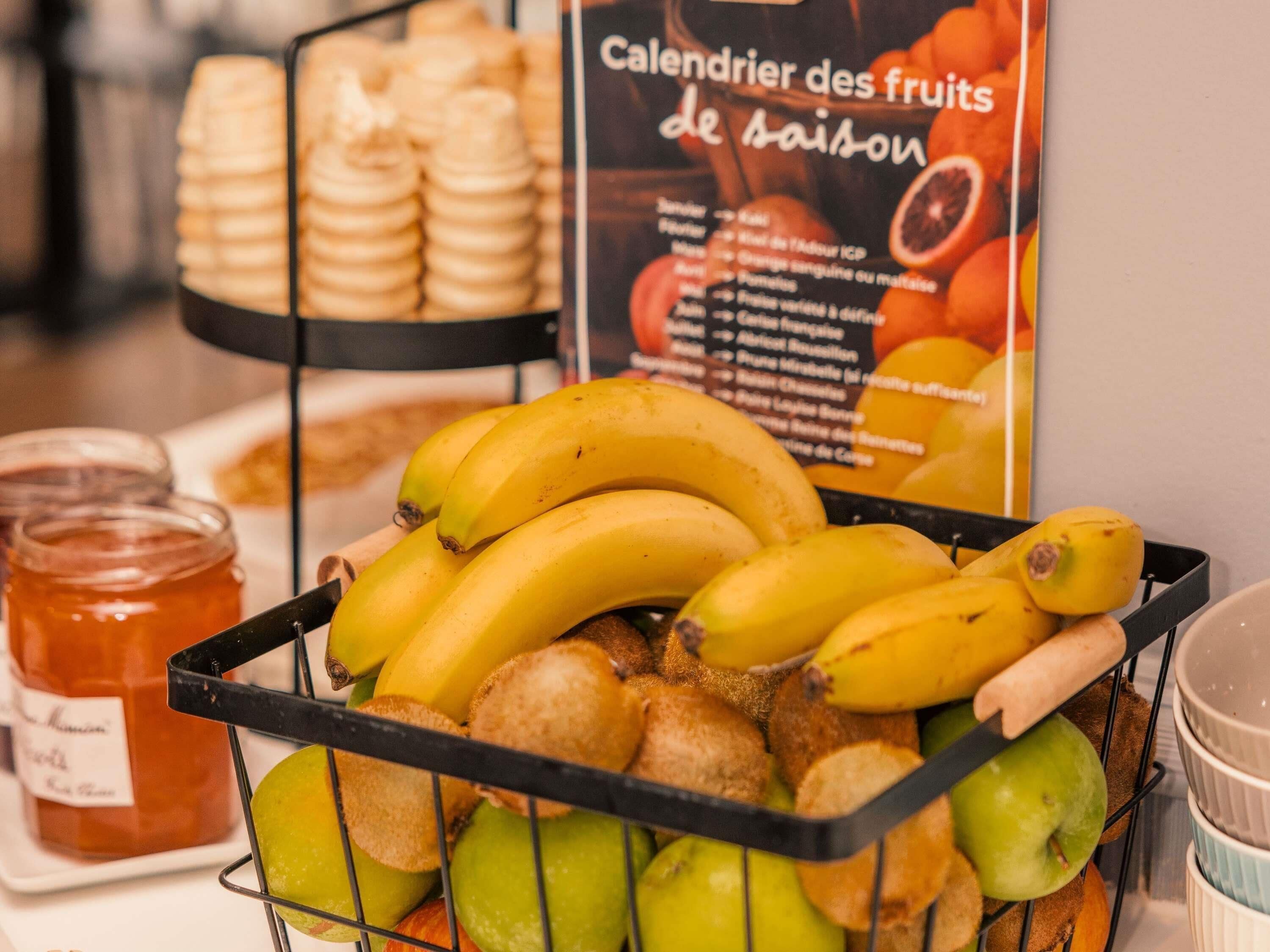 Una exposición de frutas con plátanos, manzanas y pan.