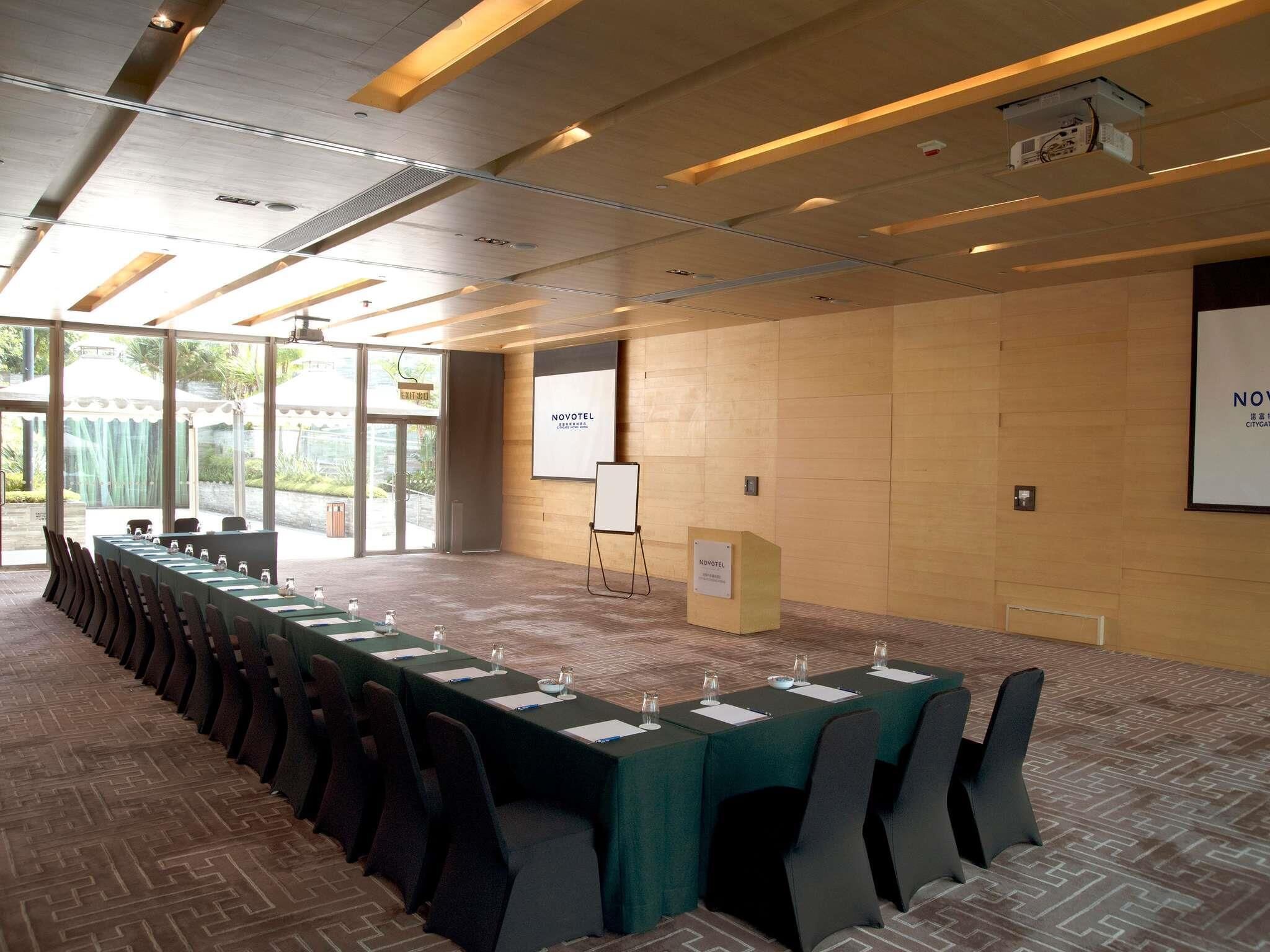 A conference room with a long table, chairs, a podium, and a projector screen.