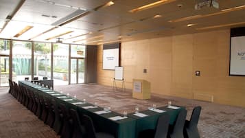 A conference room with a long table, chairs, a podium, and a projector screen.