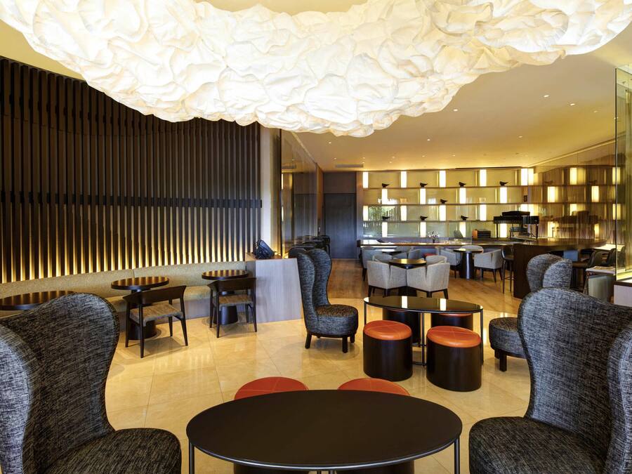 A modern interior with a seating area, a bar, and a kitchen visible through a glass partition.