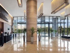 Un hall d’entrée moderne avec une colonne centrale, un comptoir d’accueil et de grandes fenêtres.