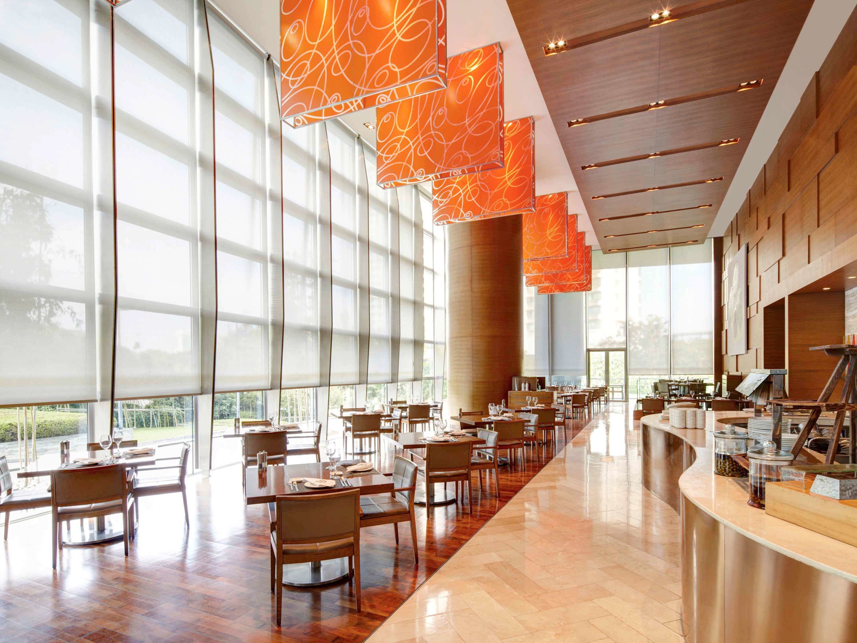 A spacious dining area with large windows, modern orange pendant lights, and a polished wood floor.
