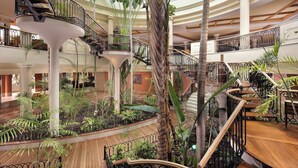 A multi-level atrium with a central garden, multiple staircases, and a variety of indoor plants.