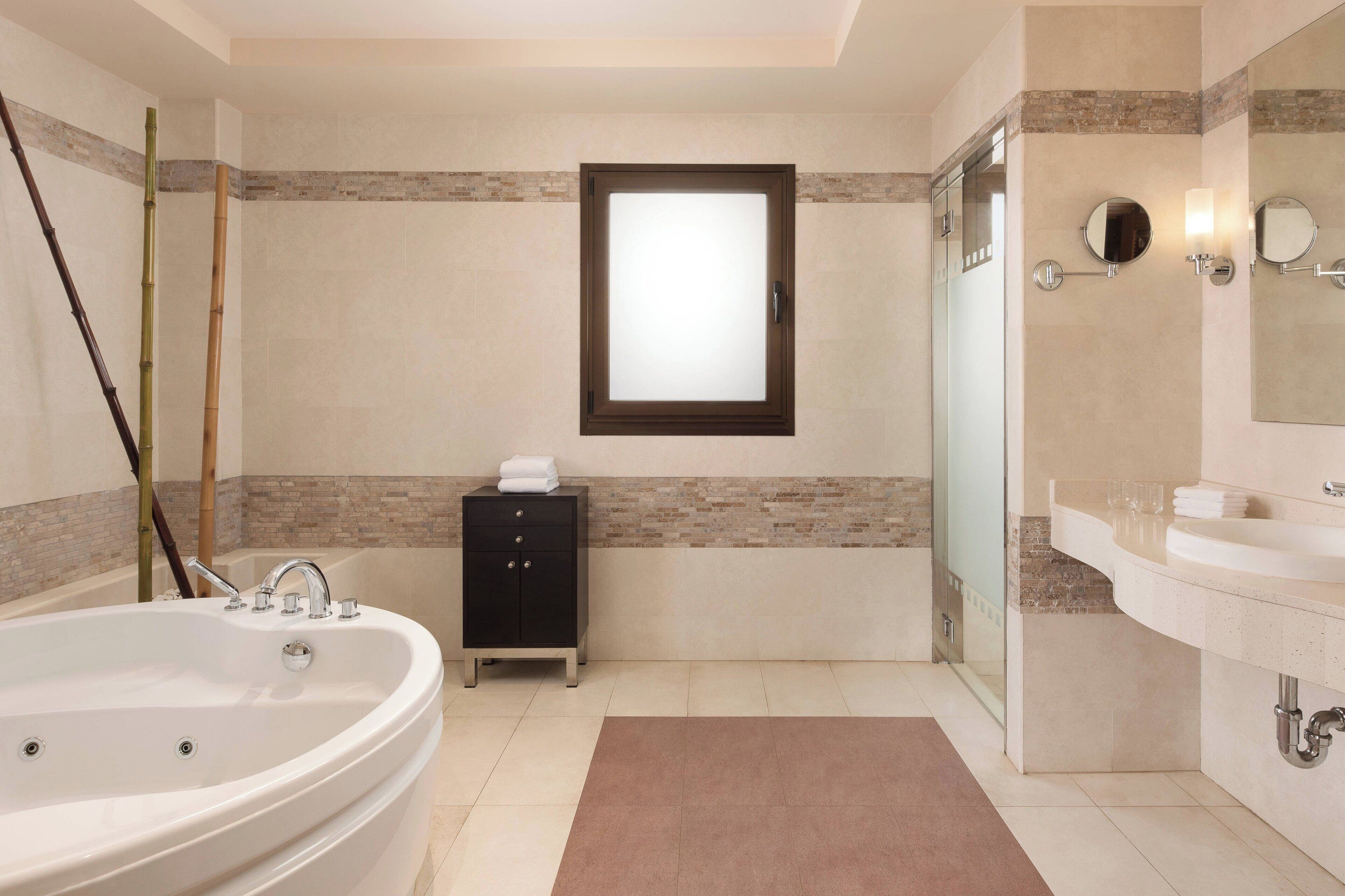 Un baño moderno con una bañera independiente, cabina de ducha con paredes de vidrio, tocador con espejo y un perchero para toallas.
