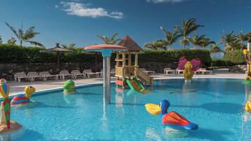Relax by the pool surrounded by lush greenery and palm trees.